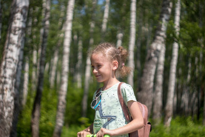 Happy girl standing by tree in forest