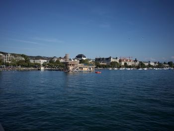 Sea by city against clear blue sky