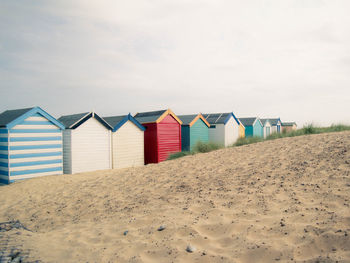 Beach huts on sand against sky