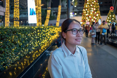 Portrait of smiling young man standing on illuminated street