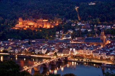 High angle view of illuminated river amidst buildings at night