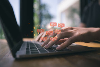 Cropped image of person using laptop on table