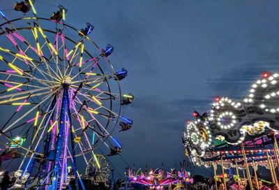 Low angle view of illuminated rides against sky at night