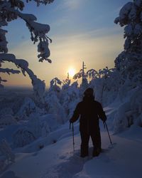 Rear view of man skiing on snow covered mountain against sky