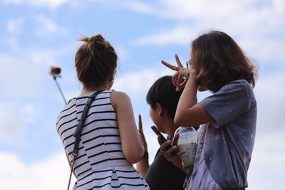 Woman taking selfie with friends against sky