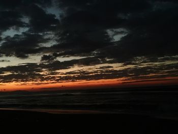 Scenic view of beach against dramatic sky