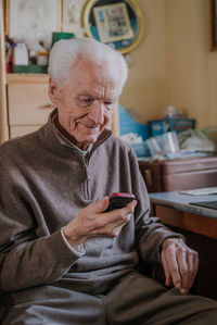 Senior man using mobile phone while sitting at home