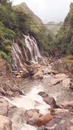 Scenic view of waterfall in forest against sky