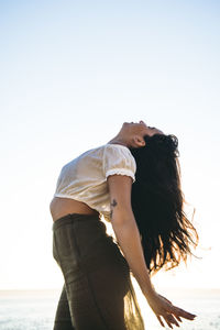 Woman standing on beach against clear sky