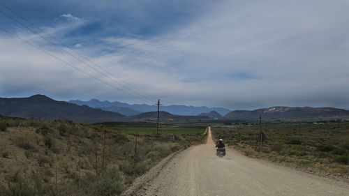 People riding bicycle on road against sky