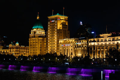 Illuminated buildings by river at night