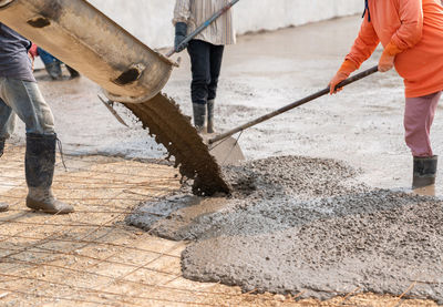 Workers pour the concrete for the construction of a road using mobile concrete mixers.