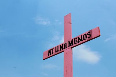 Low angle view of road sign against blue sky