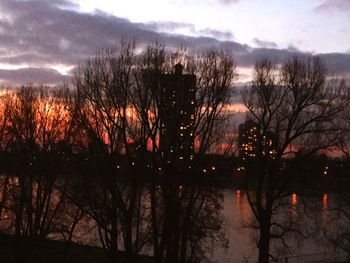 Silhouette trees by lake against sky during sunset