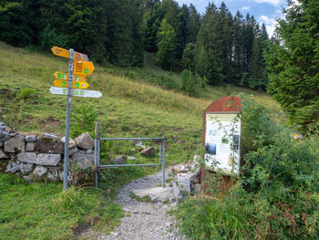 Road sign by trees on field