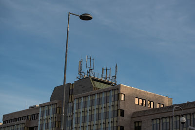 Low angle view of street light by building against sky