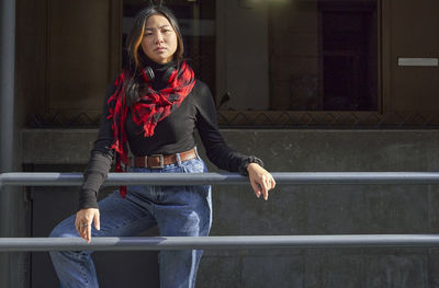 Portrait of young woman standing against railing
