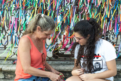 Portrait of two women placing colored ribbons on the church grid. 