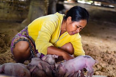 Mid adult woman crouching by piglets at farm