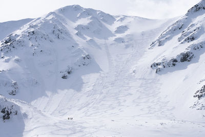 Three hikers during winter standing at the bottom of snowy mountain , slovakia, europe