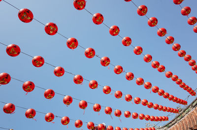 Low angle view of lanterns hanging against clear blue sky