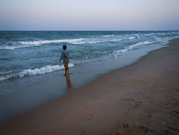 Rear view of man on beach against sky