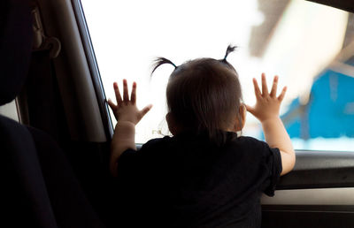 Rear view of baby girl looking through car window
