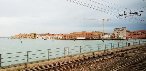 Railroad tracks by buildings in city against sky