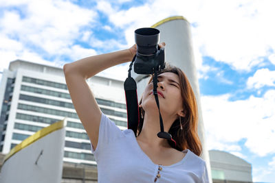 Woman photographing against sky
