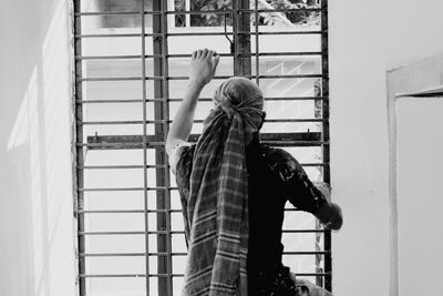 Rear view of man climbing window