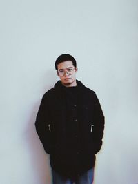 Portrait of young man standing against white background