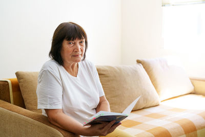 Young woman using laptop while sitting on bed at home