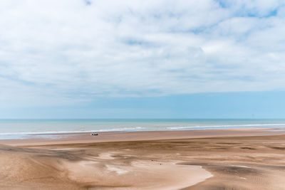 Landscape picture of the sands and dunes in front of the sea with some sky clouds.