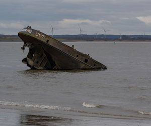 Abandoned ship on beach against sky