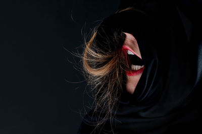 Close-up of woman screaming against black background