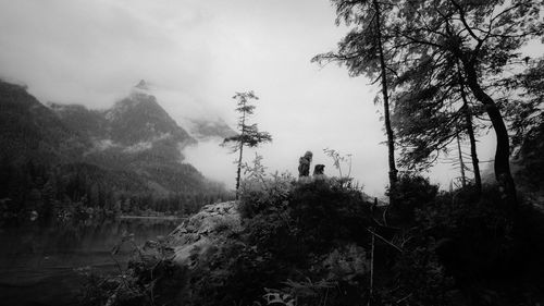 Woman and dog against cloudy mountain range at lake hintersee