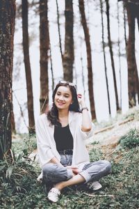 Portrait of young woman sitting on land in forest
