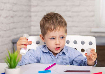 Portrait of boy sitting on table at home