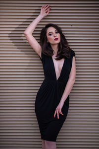 Portrait of beautiful young woman standing against wall