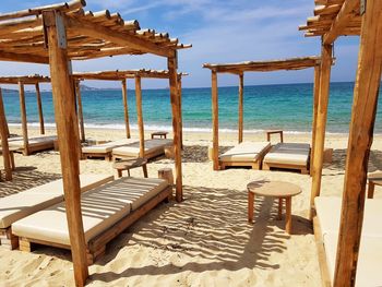 Chairs on beach by sea against sky