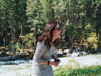 Side view of young woman standing on mobile phone