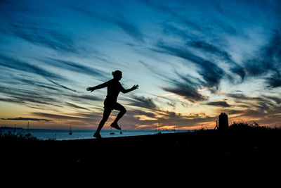 Side view of man jumping against sky during sunset