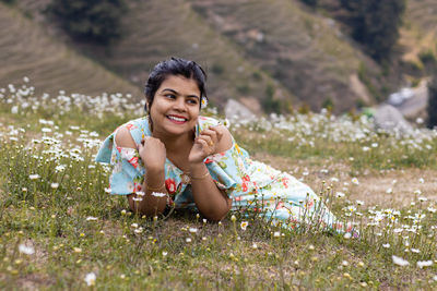 Portrait of young woman lying on grassy field