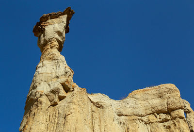 Low angle view of rock formation against clear blue sky