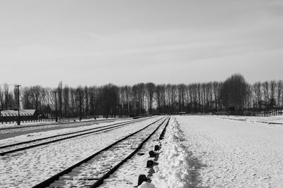 View of railroad tracks on snow covered field against sky
