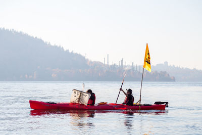 Men fishing in lake against sky