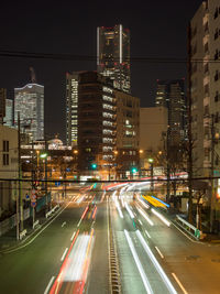 Light trails on city street by buildings at night