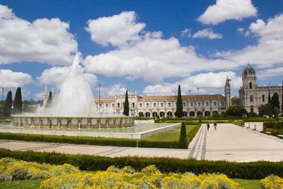 View of fountain in city against cloudy sky