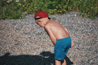 Rear view of shirtless boy standing on land