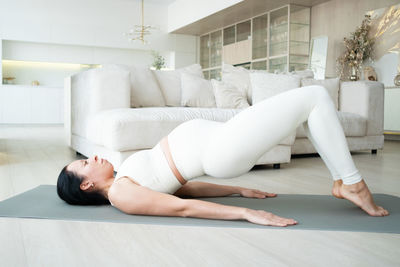 Side view of young woman exercising at home